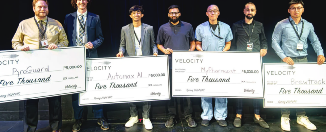 At the Velocity Final Pitch competition, six individuals stand on stage holding large checks from Velocity. Each check is for five thousand dollars, awarded to groups like PyroGuard and Automa AI. They are all smiles against a dark background, celebrating their innovative contributions to firefighter safety.