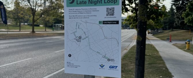 A signpost with a map for the "Route 91 Late Night Loop" stands on the sidewalk, under a partly cloudy sky, with trees lining the street. This successful campaign features a QR code and route details to enhance your late night bus experience.