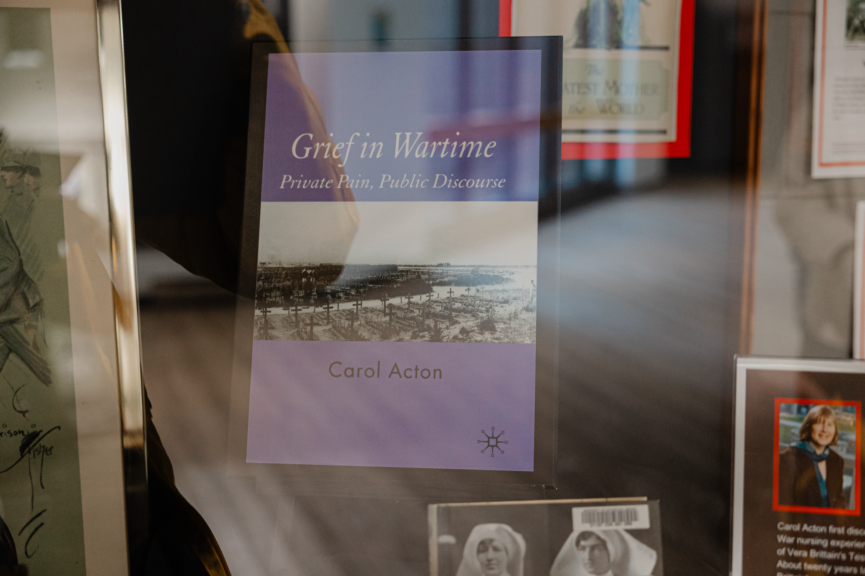 A display case at St. Jerome’s University features the book "Grief in Wartime: Private Pain, Public Discourse" by Carol Acton. The cover, surrounded by framed pictures, depicts a black-and-white wartime scene—a poignant nod to Remembrance Day and the sacrifices of wartime nurses.