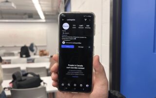 A person holding a smartphone displays an Instagram profile named "uwimprint" against a blurred classroom background. The screen reveals a message about restricted content visibility in Canada, highlighting the impact of the Online News Act on student publications.