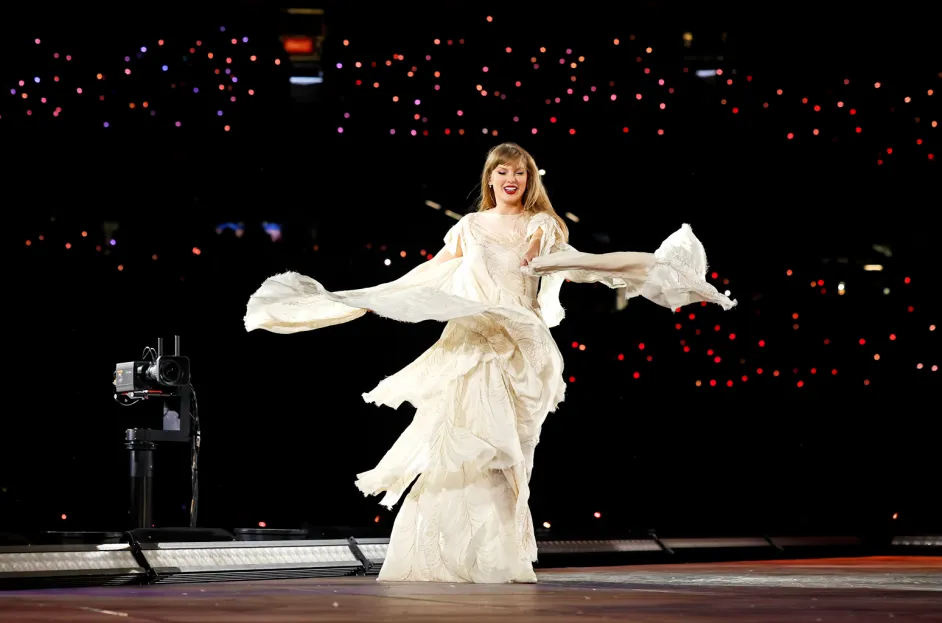 A performer in a flowing white dress twirls on stage, surrounded by dim lights and a backdrop of glowing audience lights, creating a dynamic and enchanting atmosphere. The event echoes the spirit of Canada's vibrant arts scene, drawing attention to ticket resale regulations.