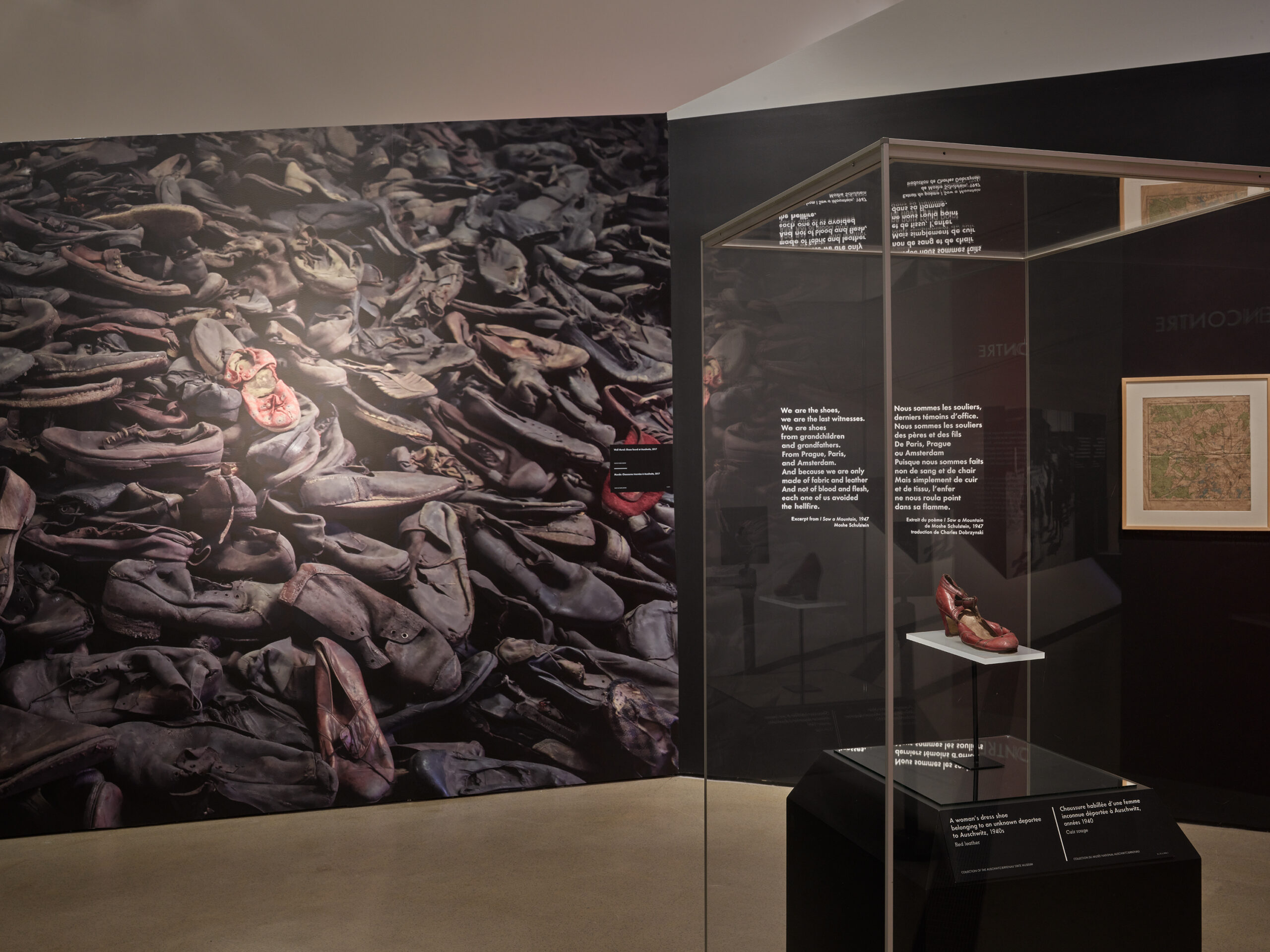 The Auschwitz exhibit features a poignant wall image of worn shoes. A glass case with a single shoe is accompanied by informative text and a framed picture, creating a solemn, historical ambiance—a tribute to the past and its stories curated by UW professor insights.