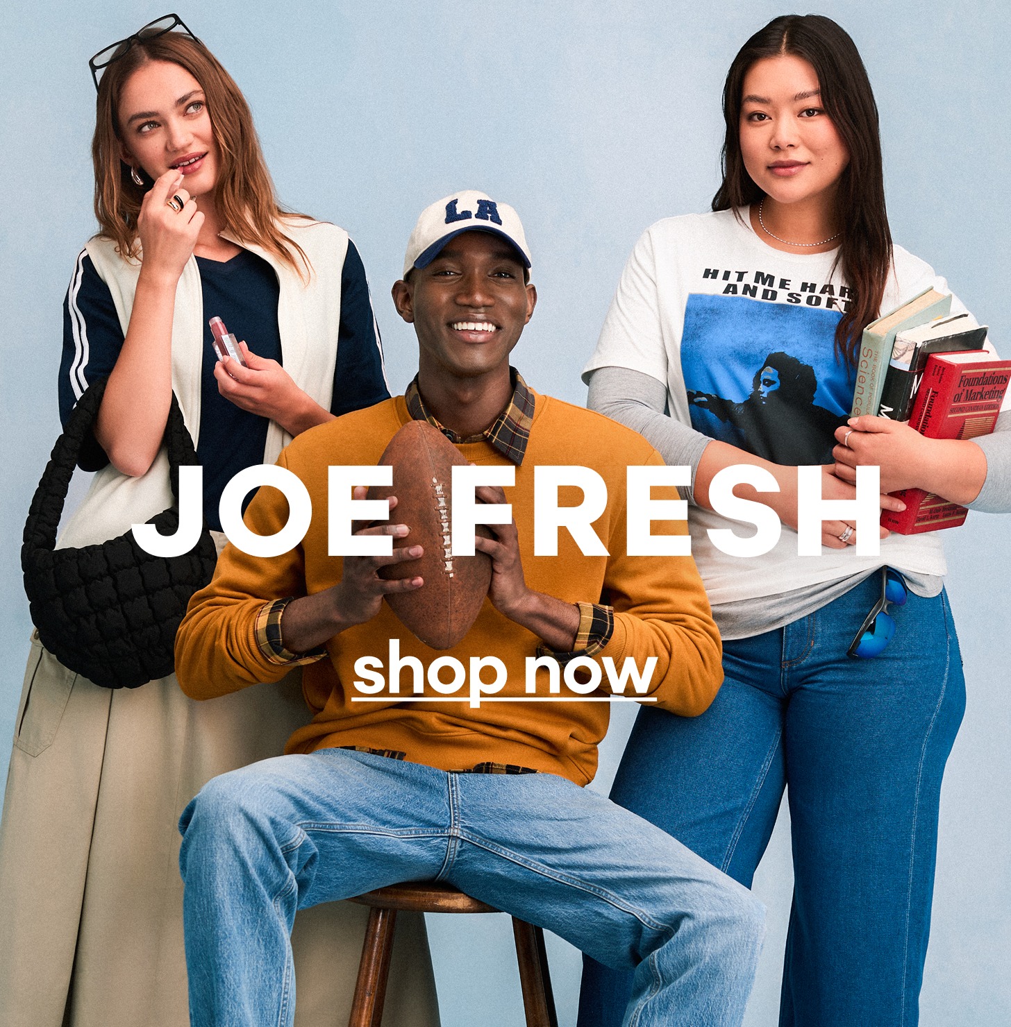 Three stylish young adults pose together, one holding a football, another with books, and the third touching her face, all smiling. The text "JOE FRESH shop now" appears across the image.