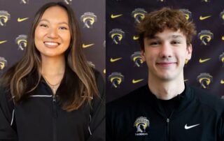 Two young adults, Athletes of the Week, smiling in front of a backdrop with a sports team and Nike logos, both wearing black zip-up jackets featuring the same team logo.